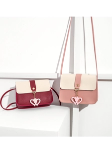 Detail of two-tone crossbody bags featuring heart charms and stylish flap design