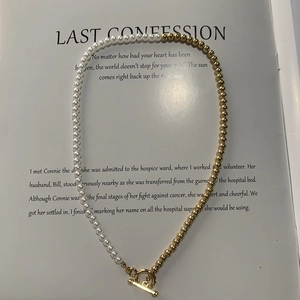 Detailed view of bicolor pearl and gold bead necklace with toggle clasp on book