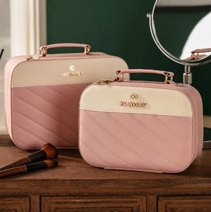 Detail of pink and beige quilted makeup cases with gold handles on a vanity table
