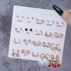 Set of minimalist gold earrings with pearls and crystals on a white display card