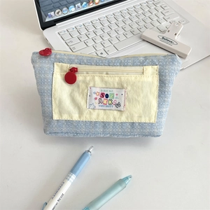 Detail of multi-layer canvas pencil case with blue grid pattern and colorful textile patch
