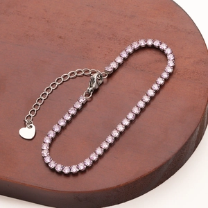Macro detail of purple gemstone tennis bracelet with silver heart charm and adjustable chain