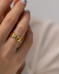 Detailed close-up of a vintage gold ring featuring three inlaid turquoise stones on a model