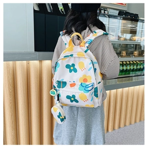 Detail of white floral kid backpack with attached coin purse and cute green charm