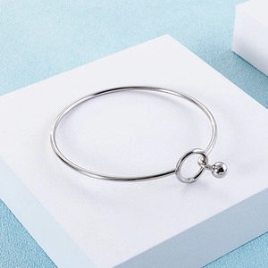 Detailed view of silver stainless steel minimalist bracelet on a light blue background