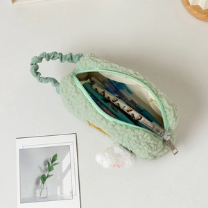 Detail of mint green plush pencil case featuring soft lamb-wool texture and pom-pom charm
