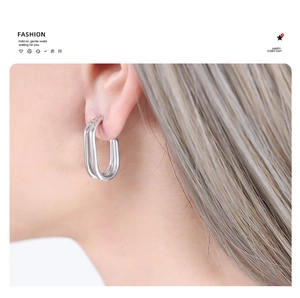 Close-up of a silver-toned U-shaped geometric earring worn by a model in a side view