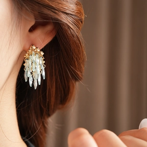 Gros plan de boucles d'oreilles dorées à pompons de cristaux bleu clair sur un modèle
