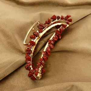 Detail of handmade banana hair claw with reddish brown stones and gold wire wrapping