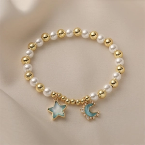 Golden bead and pearl bracelet featuring blue enamel star and moon charms with small diamonds