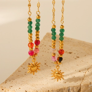 Detailed close-up of golden sun pendants and colorful stone beads on a beige stone base