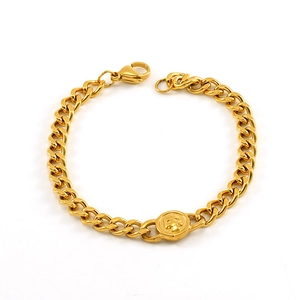 Detail view of gold Cuban link bracelet with a skull emblem and secure lobster clasp