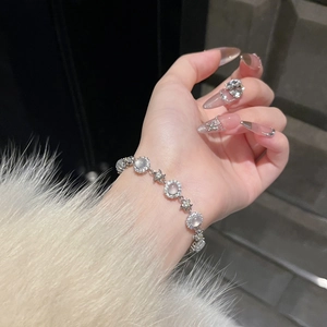 Detail of silver bracelet with zircon flowers and star charms on a woman's wrist