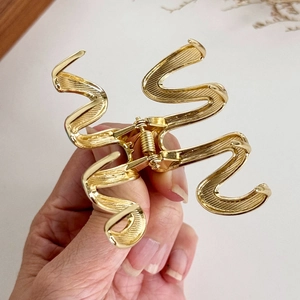 Pinza per capelli dorata ondulata in metallo lucido con elegante finitura spazzolata