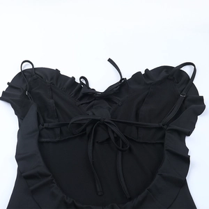 Close-up of the black backless dress showing layered ruffles and lace-up strap details