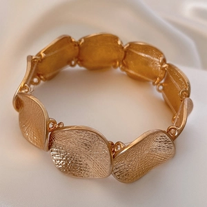 Bracciale dorato minimalista con trama in metallo martellato su sfondo di seta