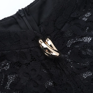 Détail de robe en dentelle noire avec motifs floraux, boucles dorées et zip invisible