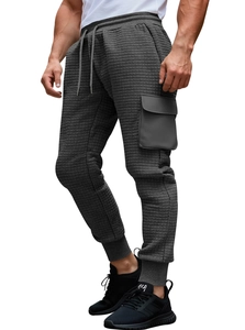 Detail of dark grey waffle texture cargo joggers featuring a side flap pocket and elastic hem