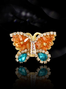 Macro view of butterfly brooch with orange crystals and pavé diamonds on gold setting