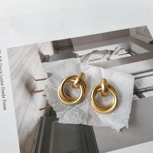 Detailed macro of gold matte triple-hoop geometric earrings with brushed finish