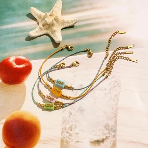 Set of four colorful woven LOVE bracelets with stainless steel beads on summer beach