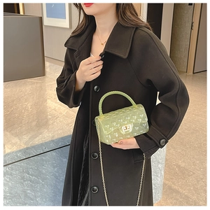 Detail of light green jelly bag with quilted pattern, gold chain and twist lock closure