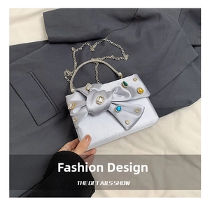 Detail showing silver grey satin evening bag with colorful crystals and a large bow design