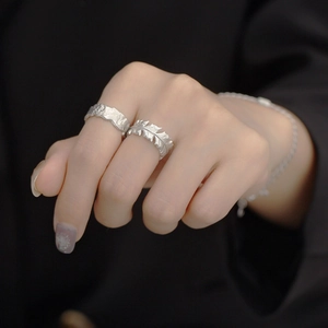 Detailed view of S925 sterling silver rings with foil texture and feather pattern on hand