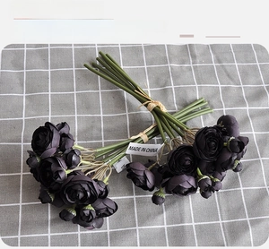 Detailed view of dark purple artificial roses tied with raffia rope and green stems