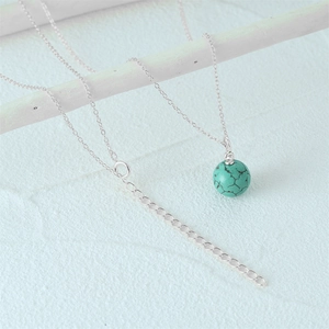 Detail of s925 silver necklace featuring a spherical turquoise pendant and zircon inlay