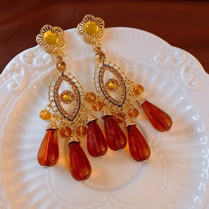 Macro detail of vintage gold-plated heart pearl earrings with amber crystal beads on ceramic