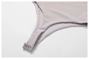 Dettaglio di body a costine color malva con bottoni a pressione in metallo argentato