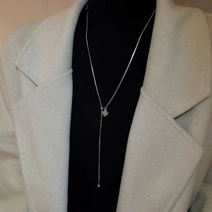 Detail of silver snake chain Y-necklace featuring snowflake slider and metal beads