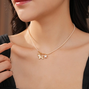 Detailed close-up of a pearl necklace with golden unicorn and crystal star pendants