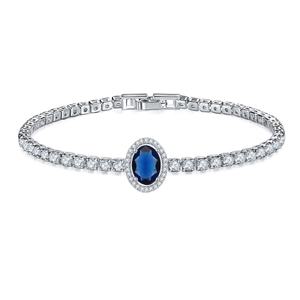 Detail of silver tennis bracelet featuring a blue oval centerpiece and halo cubic zirconia