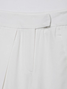 Close-up of white linen pants waist area showing fine stitching and fabric texture