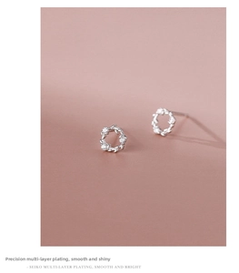Macro detail of silver floral wreath earrings with sparkling zircons and polished finish