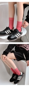 Detailed knit texture of pink crew socks styled with black sneakers on a model