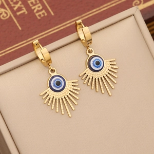 Detailed close-up of golden sunburst evil eye hoop earrings on a beige jewelry box