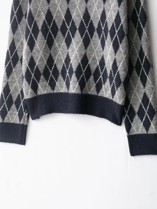Detailed view of the ribbed hem and classic argyle pattern on a knitted long sleeve sweater