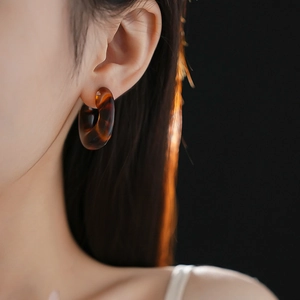 Close-up of leopard print resin C-shaped hoop earring worn by a female model