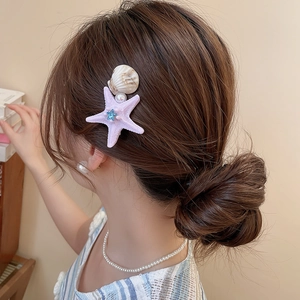 Close-up of a starfish hair clip with beige shell and pearl on a woman's hair