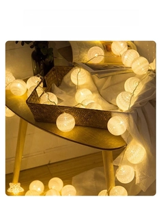 Detail of warm white cotton ball string lights on a wooden table for home decor