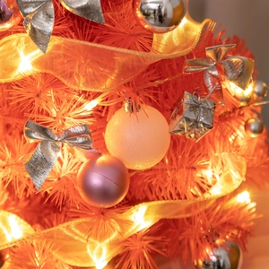 Detail of mini orange Christmas tree with silver bows, pink ornaments, and LED lights