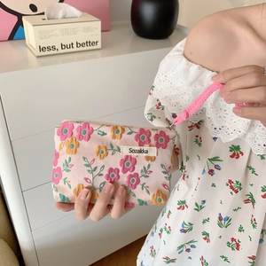 Detail of floral canvas lipstick pouch featuring a pink knotted handle and Sozakka tag