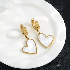 Elegant gold titanium steel hoop earrings with white shell heart charms on white ceramic plate