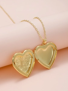Macro detail of an open golden heart locket necklace with intricate floral embossed patterns