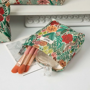 Detail of floral embroidery toiletry bag showing makeup brushes and zipper closure