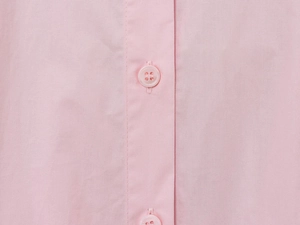 Detail view of pink poplin fabric texture and matching four-hole buttons on the shirt