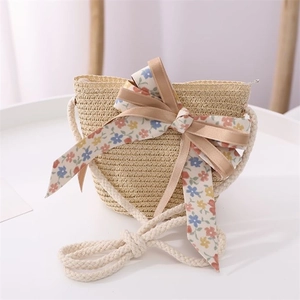 Detail of a straw crossbody bag for kids with floral bow and cotton rope strap